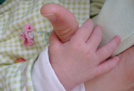 baby hand holding a parent's thumb