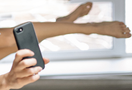 phone held in hand, bare legs in background