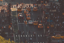 overhead view of busy city intersection full of pedestrians, taxis and other vehicles