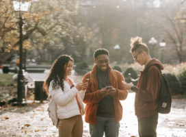 three people outside on phones