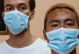 two young dark-skinned men wearing medical masks