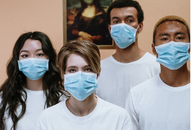 four young adults of different races wearing white t-shirts and masks